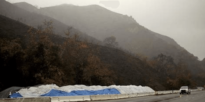 Evacuation barriers and debris flow protection on highway below wildfire burn scar during storm threat