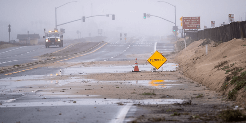 Flooded road sign warning ‘Flooded’ in California during heavy storm